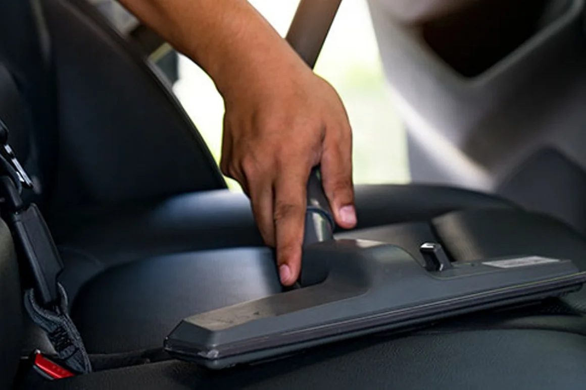 Hand reinigt Autositz mit Staubsauger